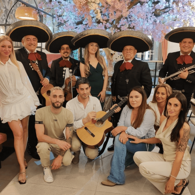 Grupo de mariachis posando con clientes en un restaurante moderno para una celebración de evento privado.
