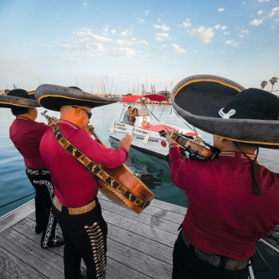 Músico profesional de Mariachi Los Reyes tocando en celebracion de cumpleaños con trajes negros e instrumentos representativos