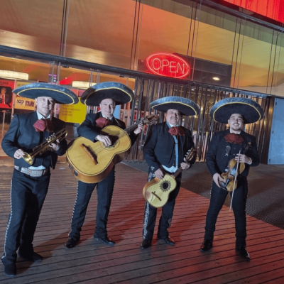 Músico profesional de Mariachi Los Reyes con trajes negros e instrumentos representativos
