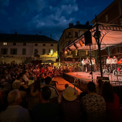 Grupo Mariachi Reyes del Mediterráneo actuando en un escenario iluminado durante un concierto nocturno al aire libre ante una gran audiencia en una plaza.