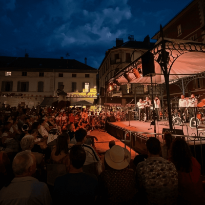 Grupo Mariachi Reyes del Mediterráneo actuando en un escenario iluminado durante un concierto nocturno al aire libre ante una gran audiencia en una plaza.