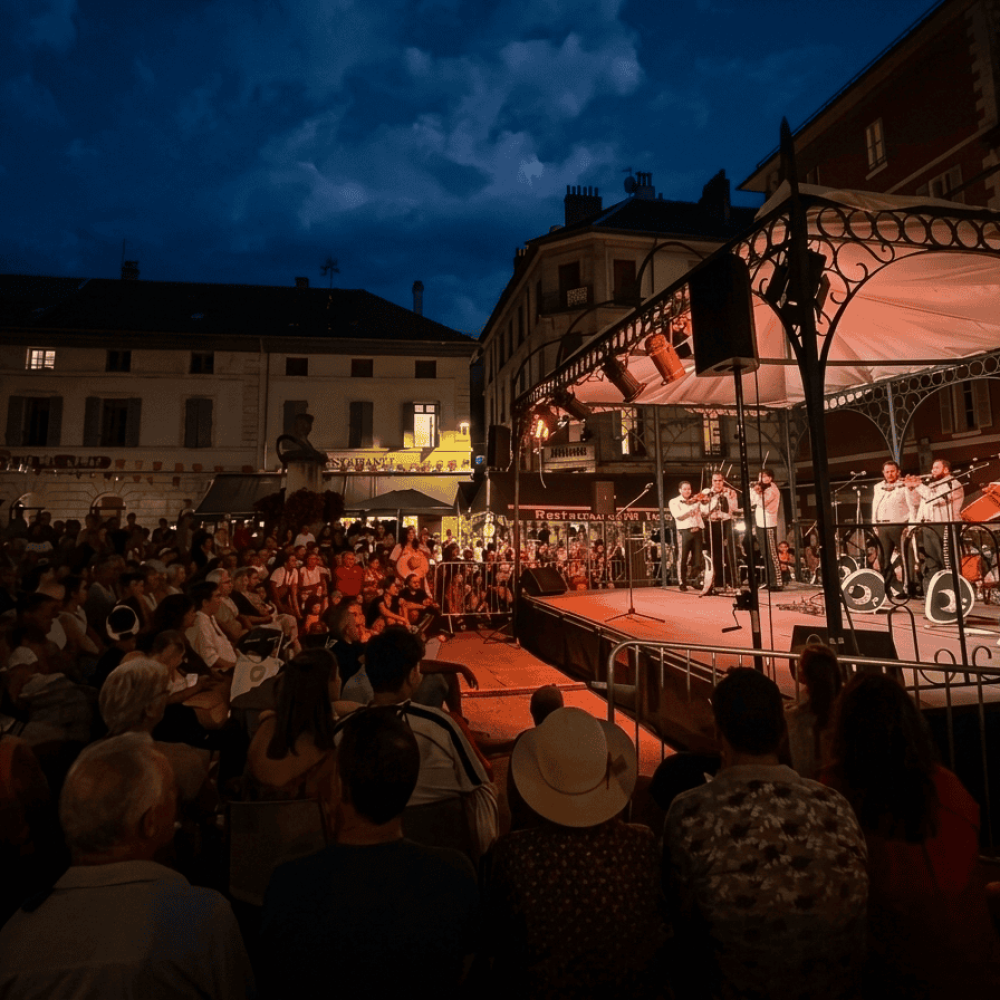 Mariachis en Elche | Serenatas, Bodas y Eventos 24H 56 Grupo Mariachi Reyes del Mediterráneo actuando en un escenario iluminado durante un concierto nocturno al aire libre ante una gran audiencia en una plaza.